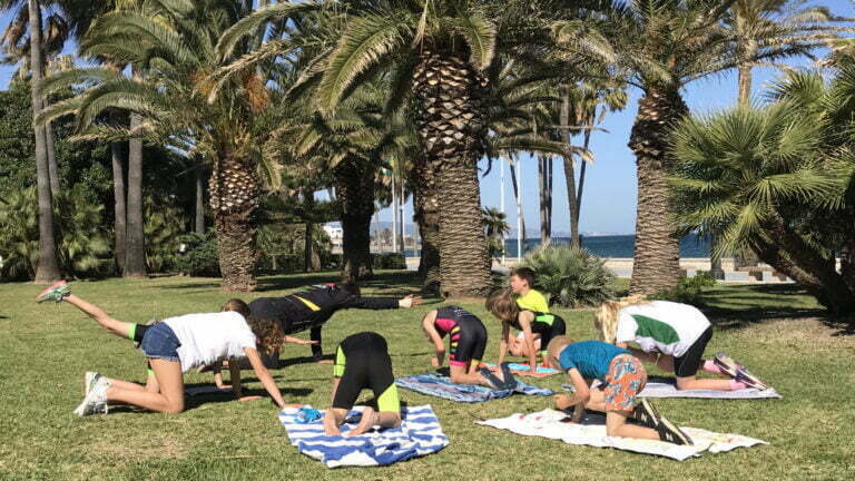 Triathlon kids doing functional training under some palm trees